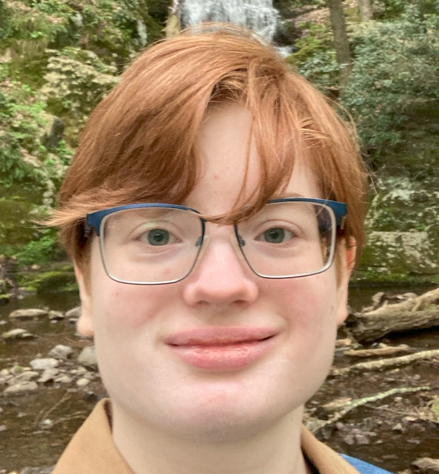 headshot image of Rose Silletto, a young person with short red hair and glasses